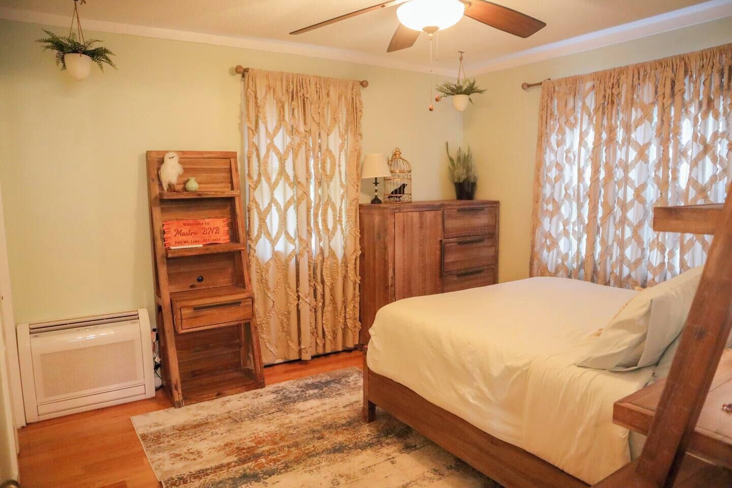 A bedroom with a bed, wooden dresser, and a ceiling fan.
