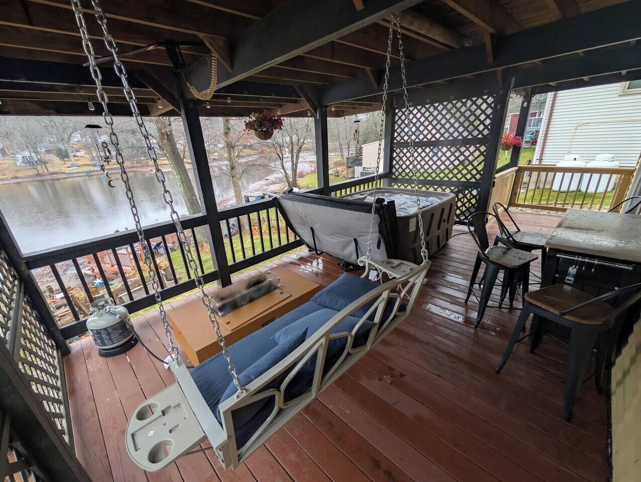 A covered outdoor seating area with a swing seat, a table, and chairs.