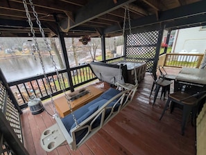 A covered outdoor seating area with a swing seat, a table, and chairs. - Lakehaven • Hot Tub, Decks, Fires & More (Plymouth)