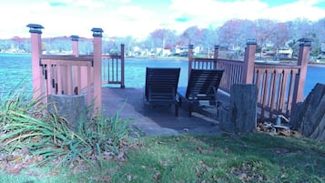 A dock with two chairs facing a body of water, surrounded by a wooden fence and vegetation.