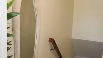 A staircase with a wooden handrail and a white wall with a large, oval-shaped mirror.