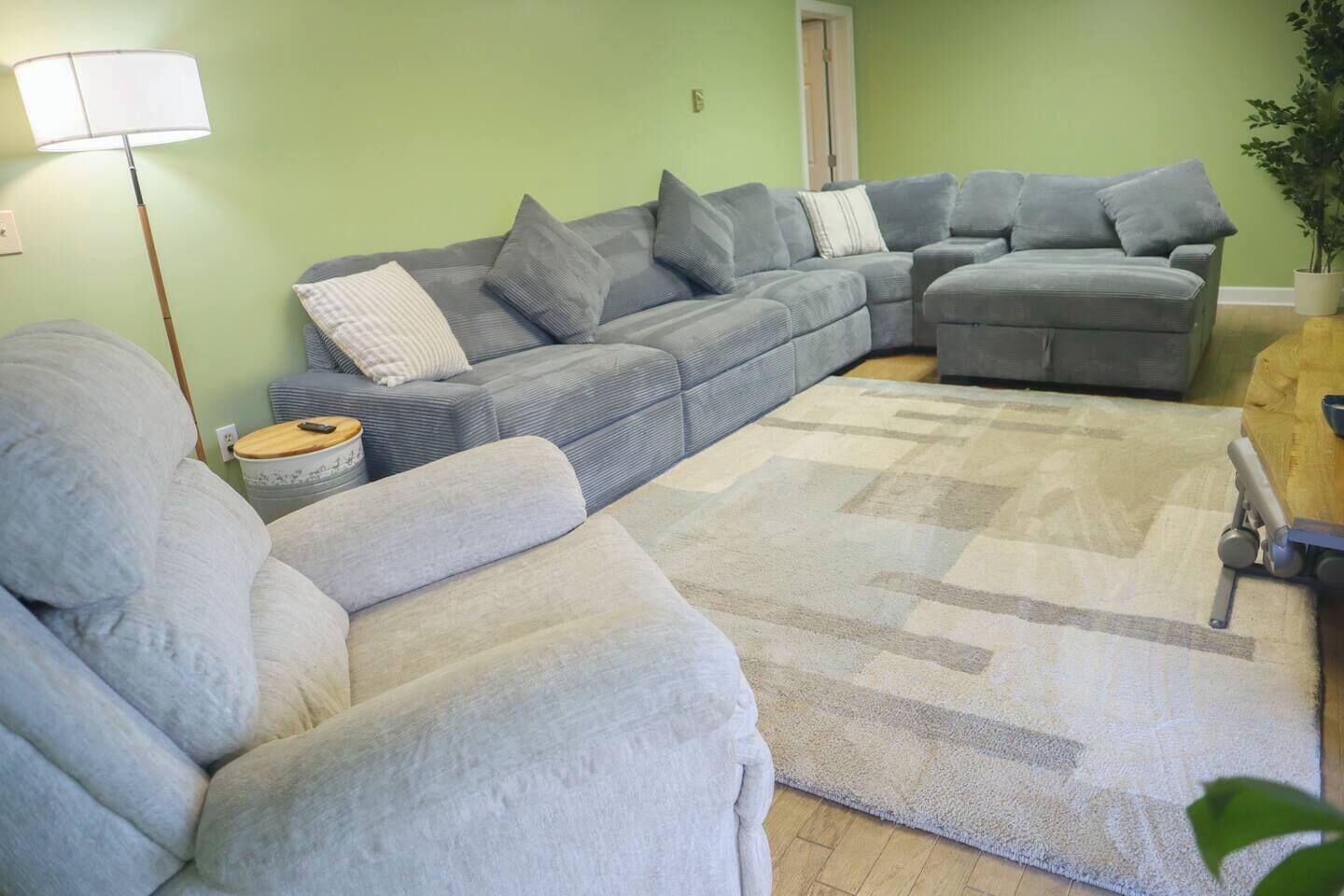 A living room with a sectional sofa, a small side table, and a floor lamp.