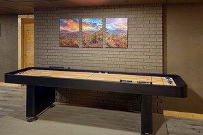 Ein Kicker-Tisch in einem Raum mit Backsteinwand und drei Bildern.