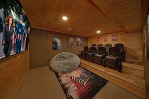 A cinema room with wooden walls, a large bean bag, and multiple movie posters. - The Oasis | Sleeps 28, Private Pool, Theater, Mtn Views, Hot Tub, Fire Pit + Free Attraction Tickets (Sevierville)