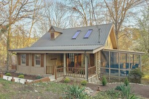 A log cabin with a porch, a covered deck, and a metal roof. - Tucked Away | Theater, Hot Tub, Arcade, Fire Pit + Free Attraction Tickets (Wears Valley)