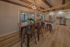 A spacious kitchen with a central island, bar stools, and a hanging light fixture. - Tucked Away | Theater, Hot Tub, Arcade, Fire Pit + Free Attraction Tickets (Wears Valley)