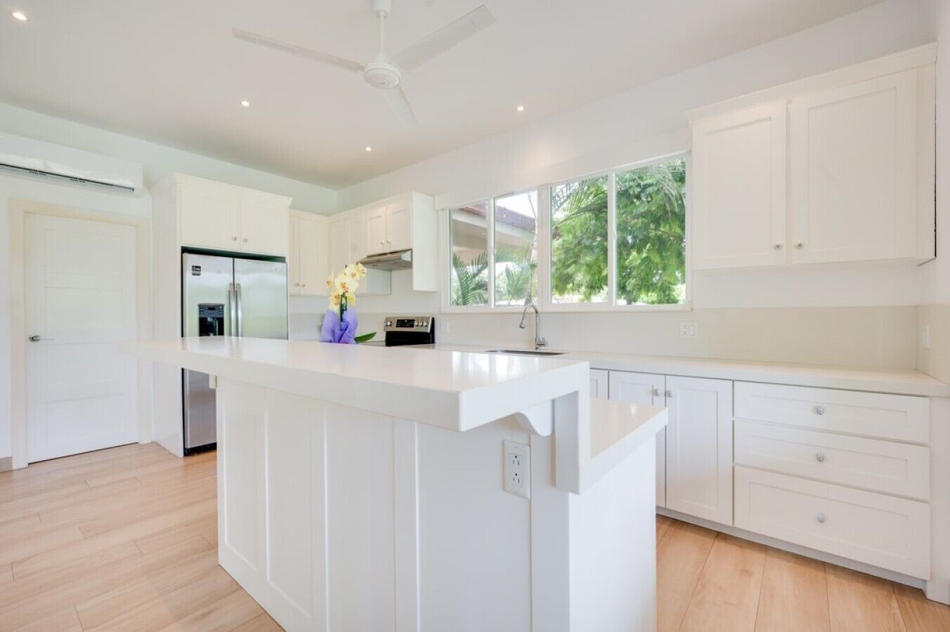 A modern kitchen with white cabinetry, a central island, and a built-in oven.