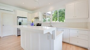 A modern kitchen with white cabinetry, a central island, and a built-in oven. - Beautiful home with pool in Rancho Cartagena! (Cartagena)