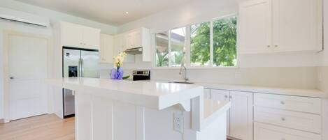 A modern kitchen with white cabinetry, a central island, and a built-in oven.