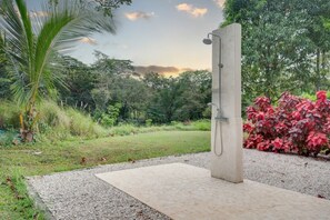 A concrete shower structure in a garden with a view of trees and a clear sky. - Beautiful home with pool in Rancho Cartagena! (Cartagena)