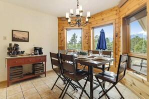Un intérieur en bois comprenant une table à manger pour quatre personnes, un coin café et une vue sur l’extérieur.
