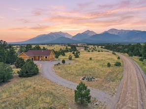 Un paysage rural avec une maison, une allée gravillonnée et un chemin de terre qui serpente à travers le champ.