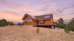 A modern wooden house with a large deck, large windows, and solar panels. - 360 Mtn Views Close to Mt Princeton Hot Springs (Nathrop)