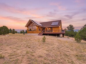 Ein modernes Holzhaus mit einer großen Terrasse, übergroßen Fenstern und Solaranlagen.