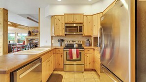A modern kitchen with wooden cabinets, stainless steel appliances, and a view of the outdoors. - 360 Mtn Views Close to Mt Princeton Hot Springs (Nathrop)