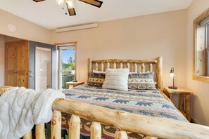A bedroom with a wooden bed frame, a patterned bedspread, and a view of the outdoors through a window. - 360 Mtn Views Close to Mt Princeton Hot Springs (Nathrop)