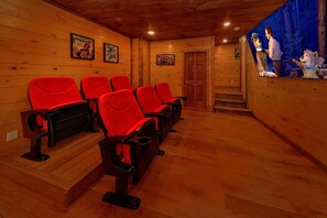 Een bioscoopzaal met houten wanden, rode zitplaatsen en een scherm waarop geanimeerde personages worden getoond.