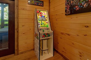 A Nintendo Switch console stand with a Mario-themed design, placed against a wooden wall with a framed comic book and a poster. - Smoky Mountain Splash | Private Pool, Theater, Hot Tub, Game Room + Free Attraction Tickets (Sevierville)