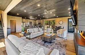 A spacious living area with a sofa, chairs, a coffee table, and a fireplace. - Ski Mountain Swim | Private Pool, Mtn Views, Hot Tub, Game Room, Sleeps 10 + Free Attraction Tickets (Gatlinburg)