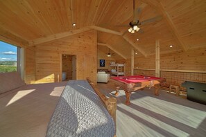 A wooden cabin interior with a pool table, bunk beds, and a ceiling fan. - Savannah Smiles Cabin Rental (Sevierville)
