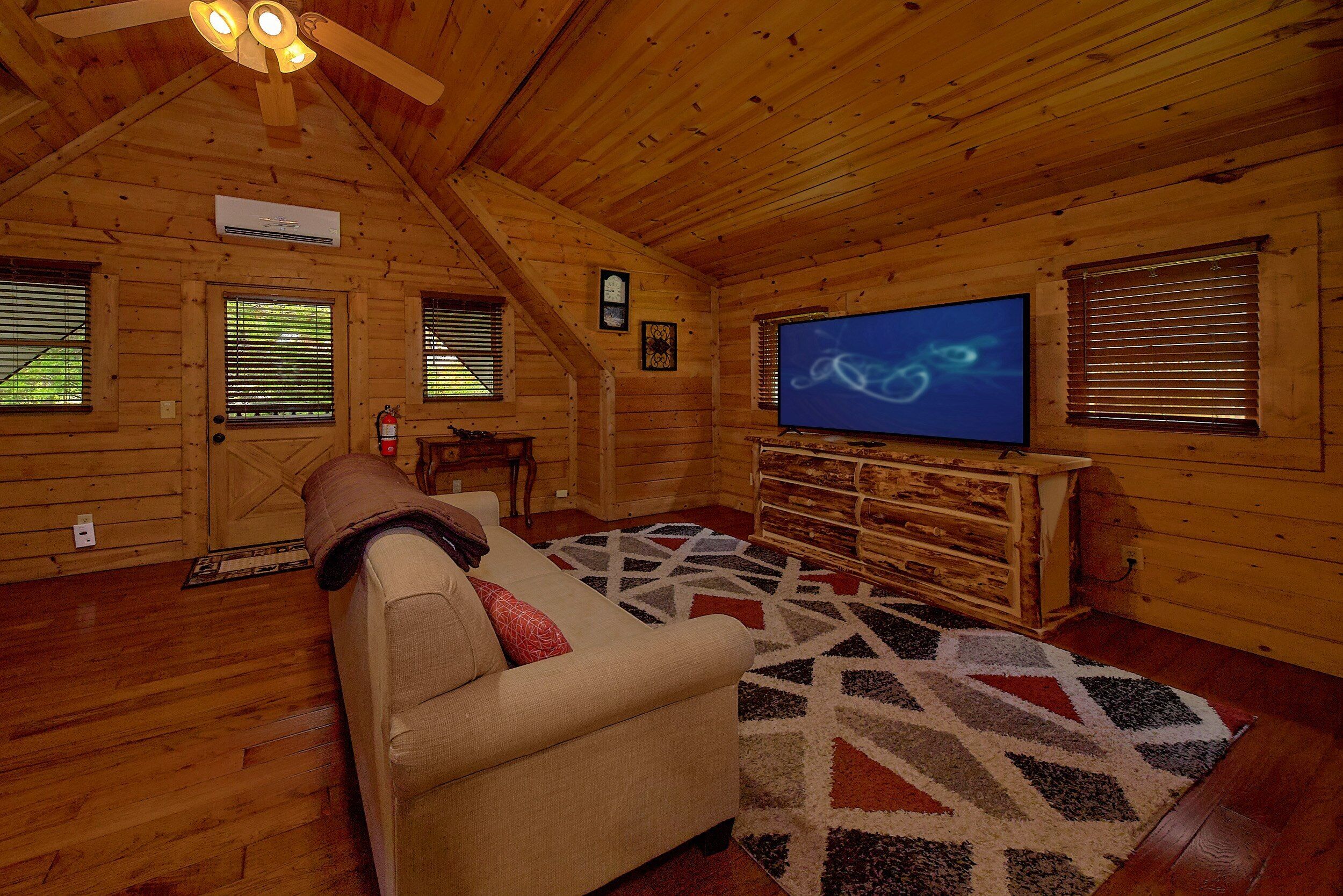 L’intérieur d’un chalet confortable, avec un canapé, un téléviseur à écran plat et un tapis à motifs.
