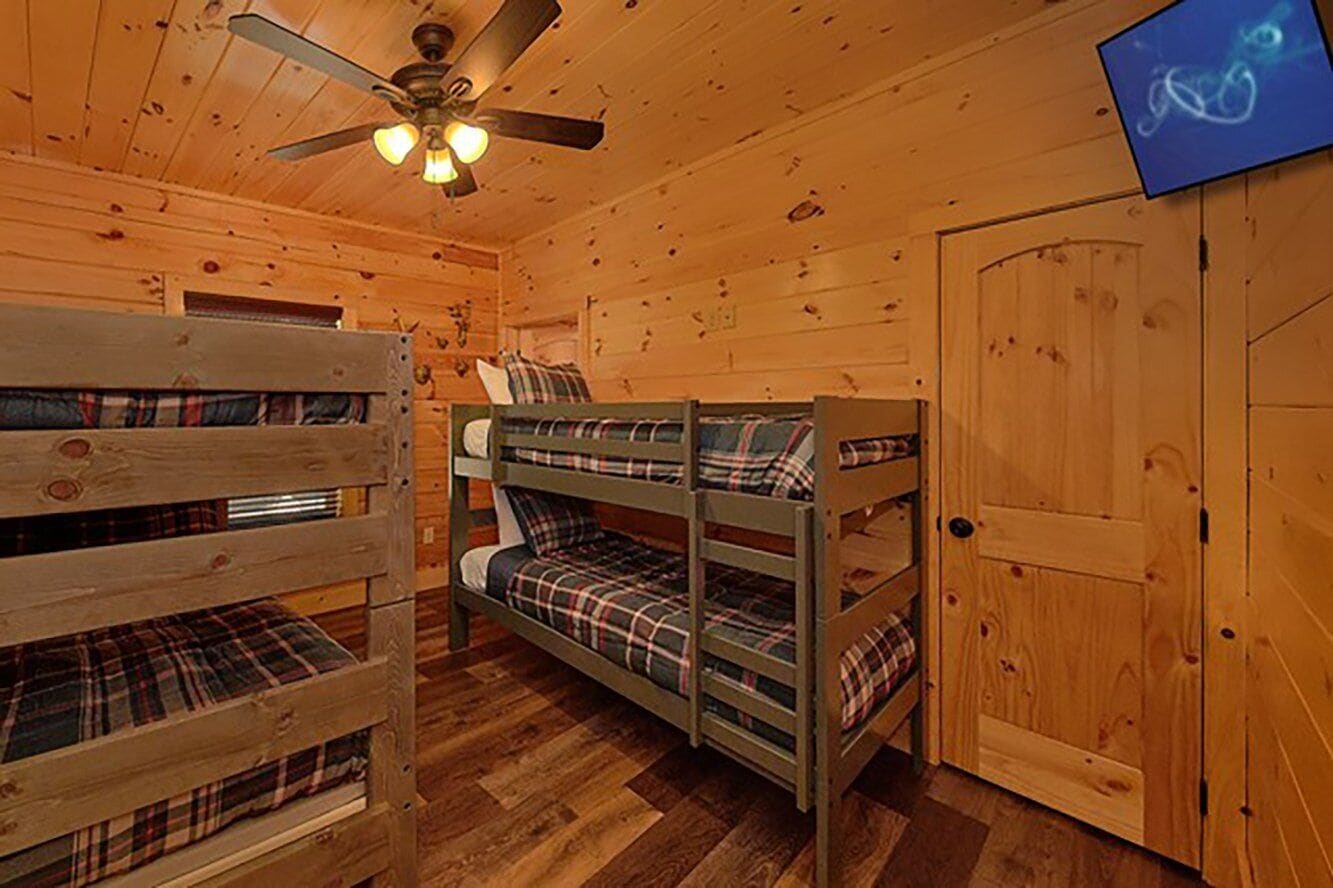 A cabin with bunk beds, a ceiling fan, and a door.
