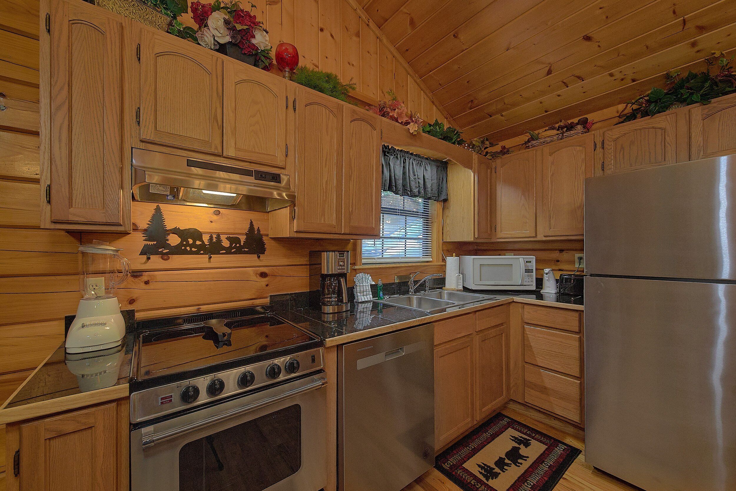 A wooden cabin-style kitchen with a stove, oven, microwave, and refrigerator.