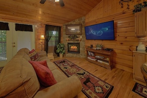 A cozy living room with a fireplace, a television, and a comfortable sofa. - Cherokee Nights Cabin Rental (Sevierville)