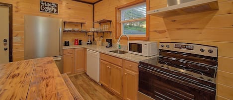 A kitchen with wooden cabinets, a stainless steel refrigerator, a microwave, a dishwasher, and a stove.