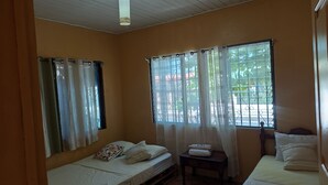 Una habitación con dos camas, una mesita y una ventana con cortinas.