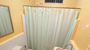 Un baño con inodoro, lavamanos y cortina de ducha.