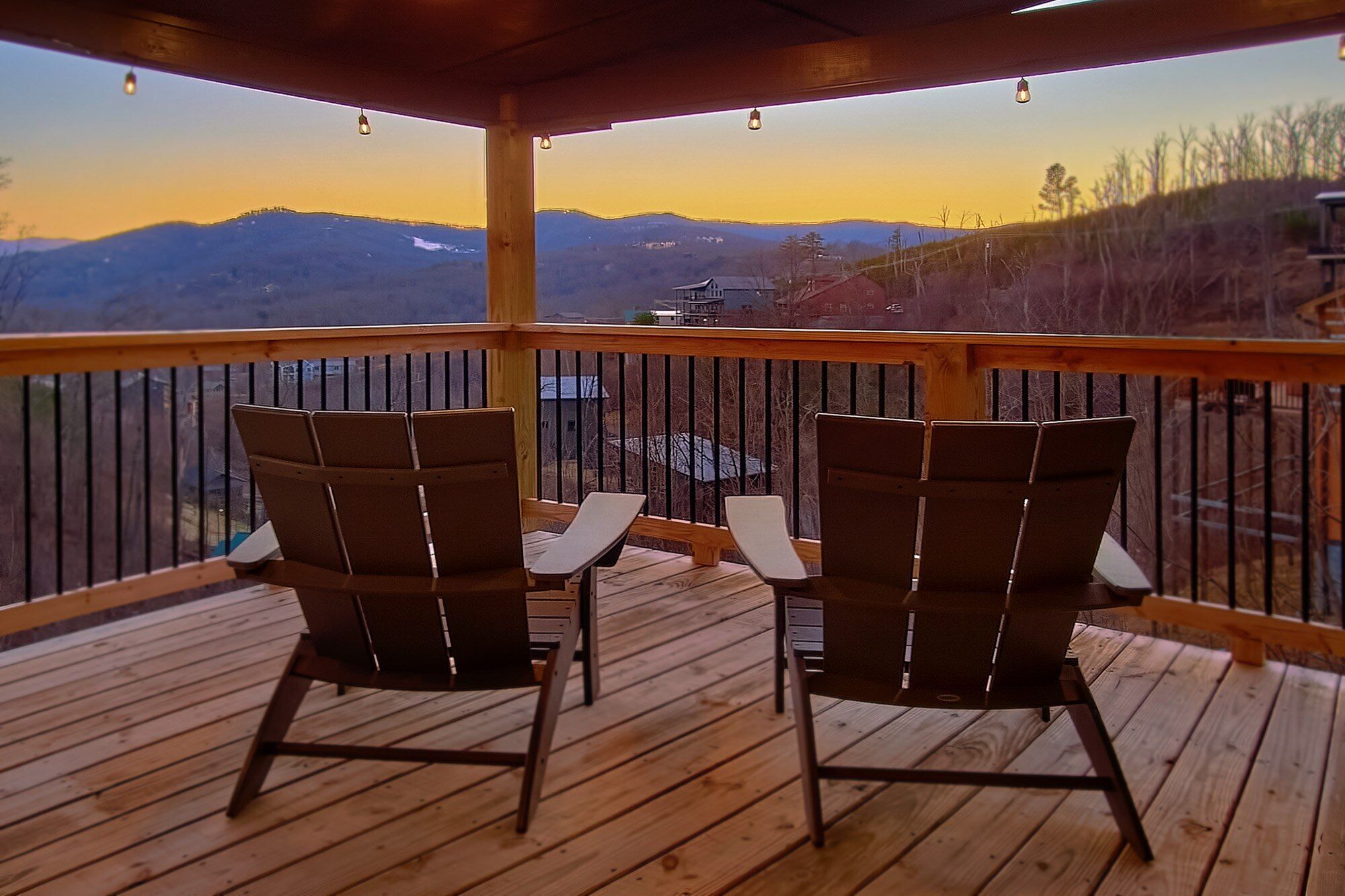 A wooden deck with two chairs facing a scenic mountain view.