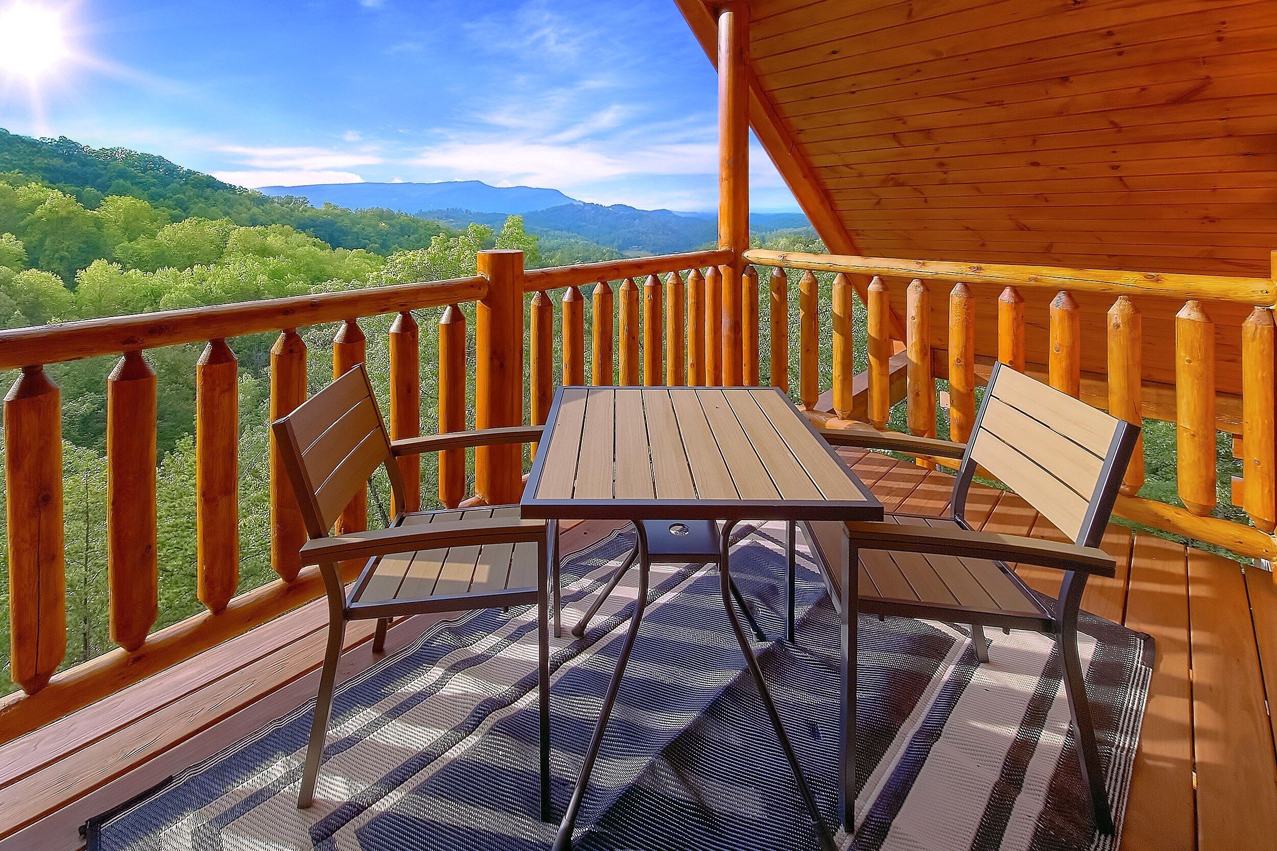 Une terrasse en bois avec une table et des chaises, offrant une vue sur un paysage montagneux.