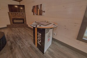 A room with a ping pong table, a television, and a fireplace. - Top Notch Cabin Rental (Pigeon Forge)