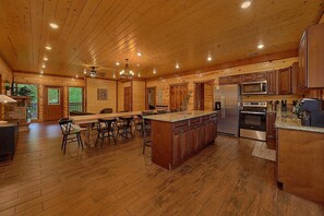 Une cuisine spacieuse avec des meubles de rangement en bois, un îlot central et un coin repas avec des chaises.