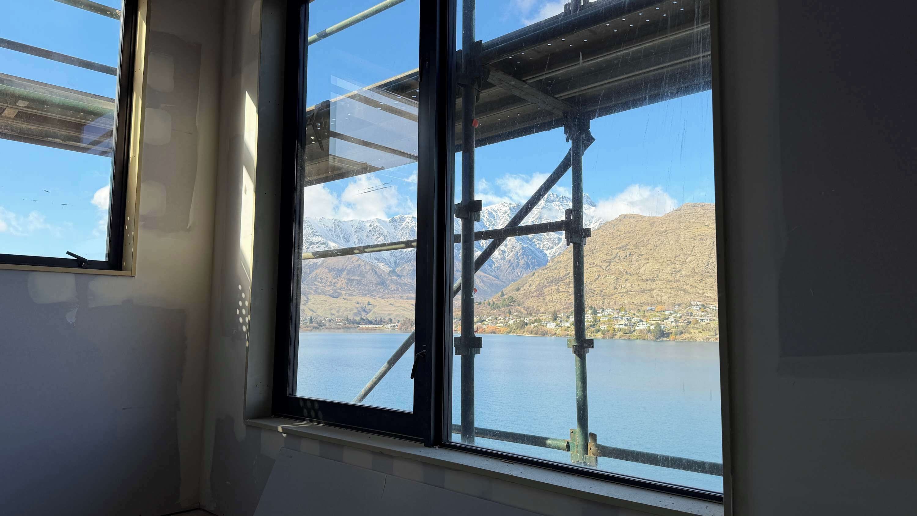 A window with a view of a mountainous landscape and a body of water.