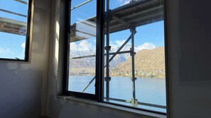 A window with a view of a mountainous landscape and a body of water. - Lakehouse 63 – Brand- New Lakefront Villa with Spa (Queenstown)