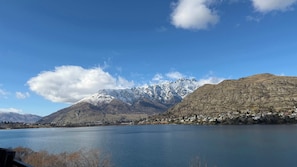 A lake with mountains in the background and a small settlement on the shore. - Lakehouse 63 – Brand- New Lakefront Villa with Spa (Queenstown)