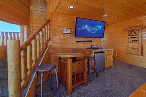 Ein Holzinterieur mit Barbereich, einem an der Wand montierten Fernseher und einer Treppe.