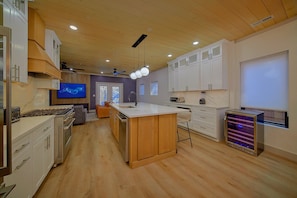 A modern kitchen with wooden cabinets, a central island, and a built-in oven. - Downtown Gatlinburg Cabin | Hot Tub, Near Downtown Gatlinburg, Game Room + Free Attraction Tickets (Gatlinburg)