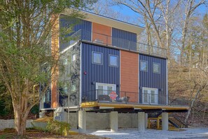 A modern two-story building with a flat roof, large windows, and a balcony. - Downtown Gatlinburg Cabin | Hot Tub, Near Downtown Gatlinburg, Game Room + Free Attraction Tickets (Gatlinburg)