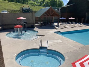 A pool area with a water feature, lounge chairs, and a covered seating area. - Lazy Bear Lodge | Hot Tub, Game Room, Resort Pool + Free Attraction Tickets (Sevierville)