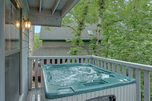 A hot tub on a wooden deck with a view of a house and trees. - Breathtaker Cabin Rental (Pigeon Forge)