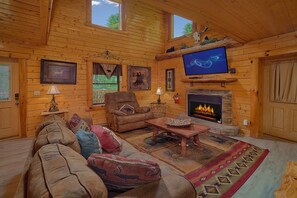 A cozy log cabin interior with a fireplace, a television, and a comfortable seating area. - Above the Rest | Game Room | Hot Tub | Fireplace (Sevierville)