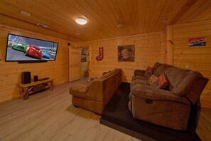 A wooden interior with a television, a couch, and a sign indicating a snack bar. - Above the Rest | Game Room | Hot Tub | Fireplace (Sevierville)