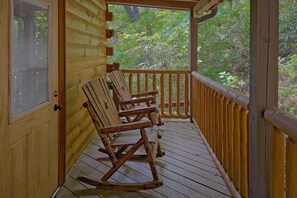 A wooden porch with a rocking chair and a window with blinds. - Above the Rest | Game Room | Hot Tub | Fireplace (Sevierville)
