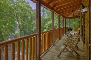 A wooden deck with a railing, a grill, and a view of trees. - Above the Rest | Game Room | Hot Tub | Fireplace (Sevierville)