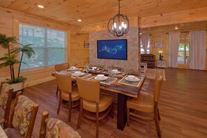 A dining area with a wooden table set for four, surrounded by leather chairs. - Amazing Mountain Cabin Rental (Sevierville)