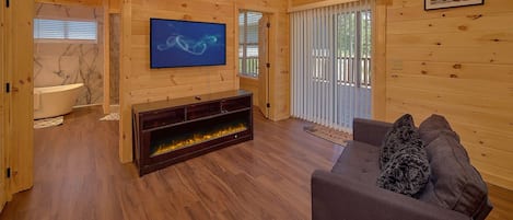 A wooden interior with a fireplace, a television, and a sofa.