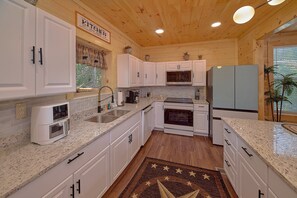 A kitchen with white cabinets, a built-in oven, a microwave, and a refrigerator. - Amazing Mountain Cabin Rental (Sevierville)